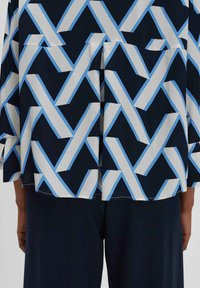 Blusa blu navy con un motivo geometrico di forme sovrapposte blu e bianche, con una vestibilità rilassata e maniche a tre quarti.