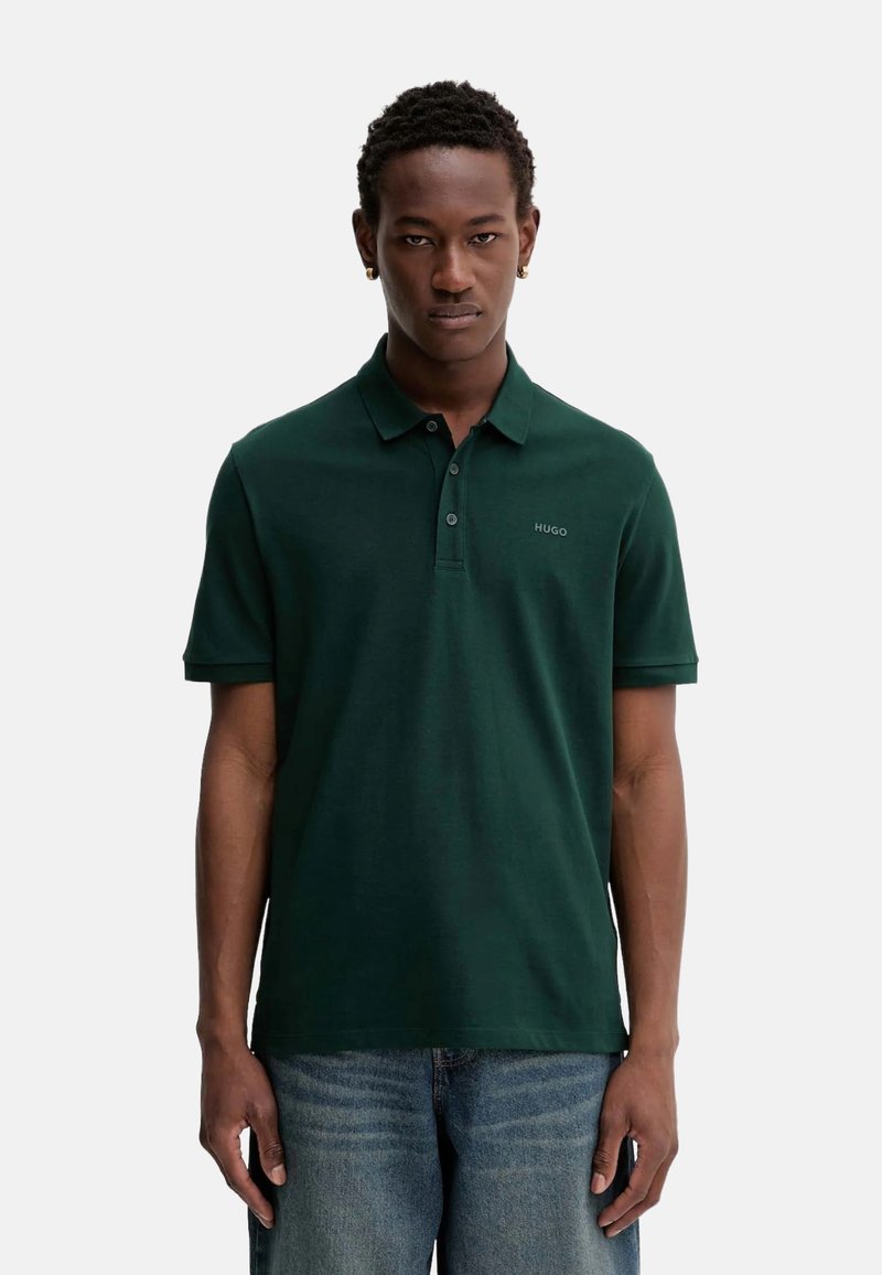 Polo de color verde oscuro hecho de algodón, con cuello abotonado, mangas cortas y un pequeño logo bordado en el pecho. Corte casual.
