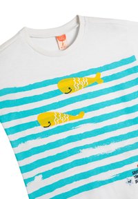 Hvid bomulds t-shirt med horisontale turkise striber og to gule fisk med sorte øjne. Har en trykt slogan nederst.