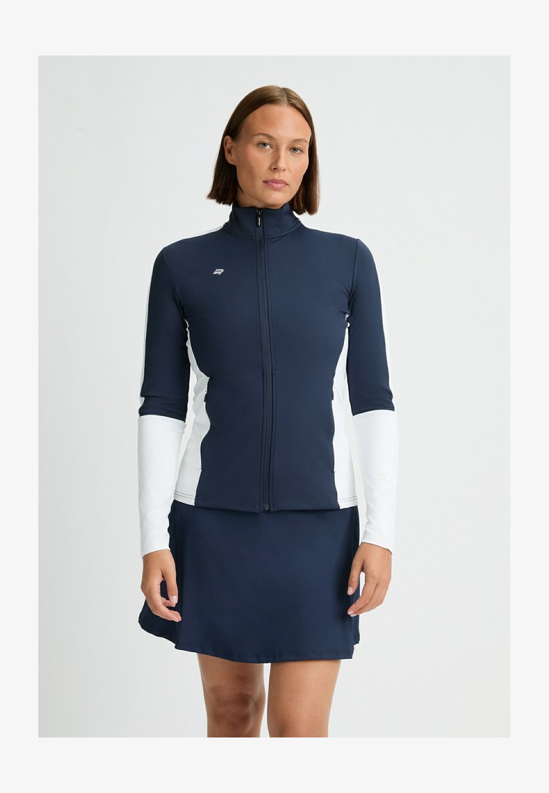 Marineblå og hvid zip-up atletisk jakke med lange ærmer og høj krave, parret med en marineblå nederdel. Glat, strækbart stof, strømlinet design.