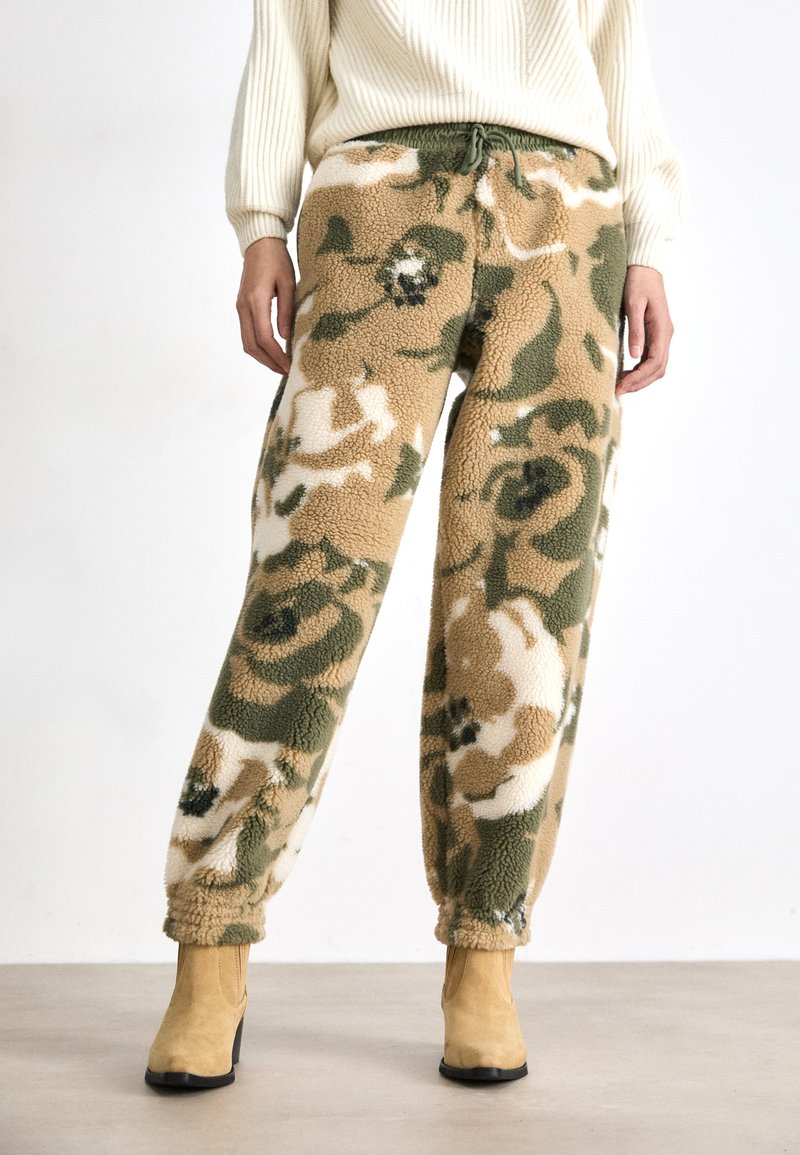 Fleecebukser med camouflage-mønster i beige, grønt og hvitt; elastisk midje med snor; avsmalnende mansjetter ved anklene.