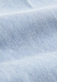 Light blue woven fabric with fine texture and subtle stripes, shown in a close-up view with gentle folds and shadows.