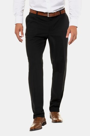 Mężczyzna idący, ubrany w czarne eleganckie spodnie, brązowy skórzany pasek i wypolerowane brązowe eleganckie buty, z włożoną do środka białą koszulą.