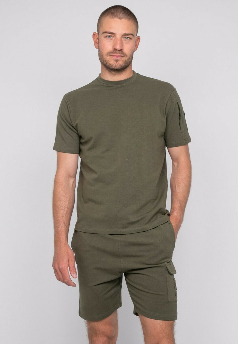 T-shirt à manches courtes vert olive et short assorti, fabriqués dans un matériau doux, dotés de poches latérales et d'un design décontracté.