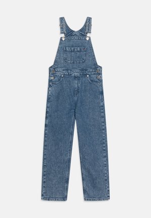 Salopette bleu en denim avec bretelles ajustables, poche poitrine avant, boutons sur les côtés et pantalon à jambes larges, étalée à plat sur fond blanc.