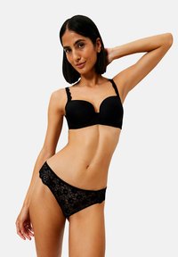 Czarny koronkowy biustonosz z formowanymi miseczkami i falbaniastymi ramiączkami, w komplecie z pasującymi czarnymi koronkowymi majtkami z akcentami w kwiatowy wzór.