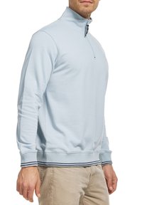 Lyseblå lynlås-sweatshirt i blødt stof med høj krave, ribbede manchetter og en tofarvet stribet kant. Enkel design uden mønstre.