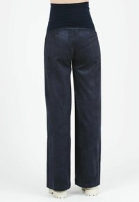 Pantaloni corduroy alti in vita di un blu navy scuro, con una cintura liscia e gambe larghe, caratterizzati da una texture a righe verticali e una vestibilità rilassata.
