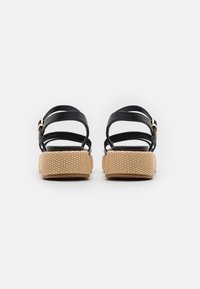 Black leather sandals featuring multiple thin straps and a buckle, with a textured beige platform sole.