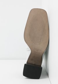 Semelle de bottine blanche avec une semelle beige légèrement texturée, talon carré noir, et l'inscription "Made in Spain 37 Topshop" embossée.