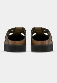 Καφέ σανδάλια από φελλό με ανοιχτή φτέρνα, πολλαπλές ανοίγματα και δύο ρυθμιζόμενα λουριά. Μαύρη ελαστική σόλα με υφή για καλύτερη πρόσφυση.