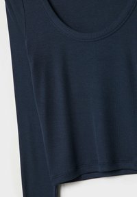 Haut à manches longues côtelé bleu marine avec un col rond. Le tissu semble doux avec une texture subtile et un ourlet légèrement court.