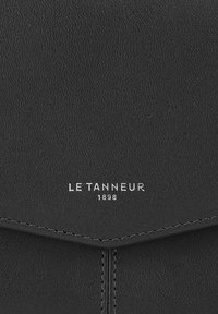Billetera de cuero negro con superficie texturizada, que presenta el logotipo en relieve "LE TANNEUR 1898" en plata y costuras en contraste.