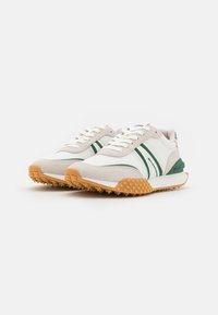Sneakers z jemné síťoviny a semiše s bílým základem, zelenými pruhy a texturovanou oranžovou podešví. Design na šněrování s polstrovaným límcem.