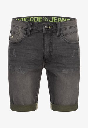 Szürke farmer rövidnadrág, elhalványult hatással, kopott részletekkel, zöld derékkal és felgöngyölt szárakkal. Az elülső zsebek láthatók.