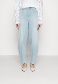 Ljusblå denimjeans med avslappnad passform, med hög midja och subtila blekningar. Matchas med spetsiga beige klackar.