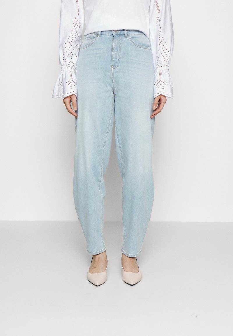 Ljusblå denimjeans med avslappnad passform, med hög midja och subtila blekningar. Matchas med spetsiga beige klackar.