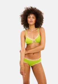 Limegrønt lingerisæt bestående af en bralette med blondekant og matchende trusse, begge med delikate detaljer og justerbare stropper.