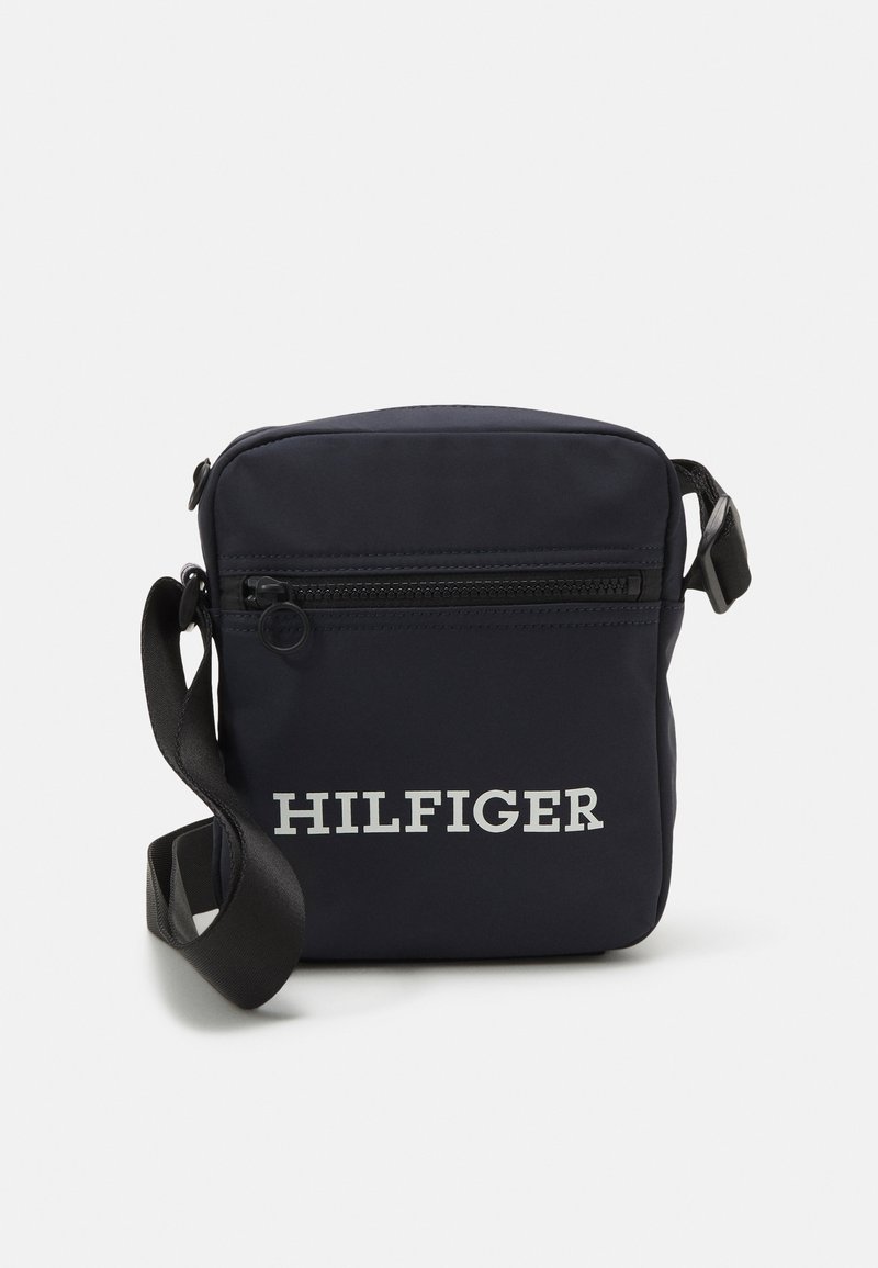 Borsa a tracolla in nylon blu navy con tracolla regolabile, dotata di una tasca anteriore con zip e logo "HILFIGER" in rilievo sul davanti.