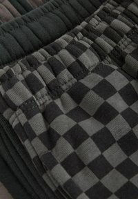 Jogginghosen mit elastischem Bund in einem strukturierten schwarz-grauen Karomuster. Weicher Baumwollmix mit gerafften Details am Bund.