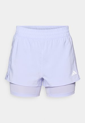 Šviesiai violetiniai sportiniai šortai su elastinga juosta, sluoksniuota konstrukcija ir integruotais vidiniais šortais; puošti baltu logotipo akcentu.