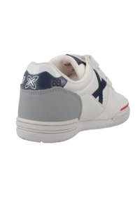 Zapatilla blanca con acentos en gris y azul marino. Presenta una superficie texturizada, una suela de goma y un logo bordado en el talón. Diseño de cordones simple.