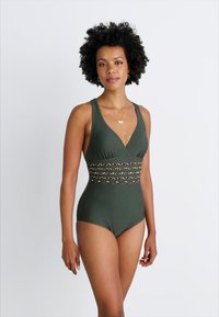 Maillot de bain une pièce vert olive avec un décolleté en V, présentant une bande en imprimé léopard à la taille et un tissu texturé.
