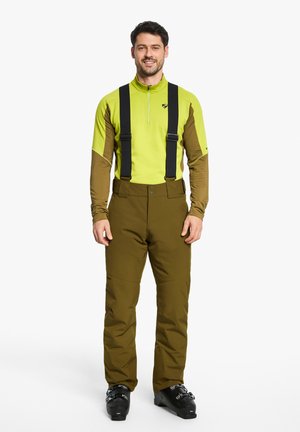 Men's skiing outfit featuring a bright green long-sleeve base layer, dark brown sleeves, and brown snow pants with black suspenders.