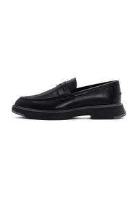 Mocasin de cuero negro con punta redondeada, costura decorativa y suela de goma texturizada. Diseño minimalista, de altura media con un aspecto apilado.