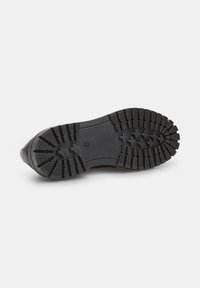 Semelle d'une chaussure noire présentant un motif de semelle robuste, avec de profondes rainures et des sections en relief pour une meilleure adhérence et traction.