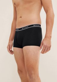Boxer neri realizzati in tessuto liscio con una vestibilità aderente. Presentano un elastico in vita grigio e bianco con marchio. Nessun motivo o accento visibile.