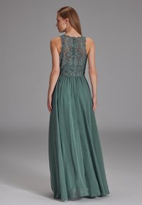 Langes grünes Kleid mit einem Spitzenoberteil mit Blumenmustern, einer taillierten Taille und einem fließenden Satinrock, der elegant bis zum Boden fällt.