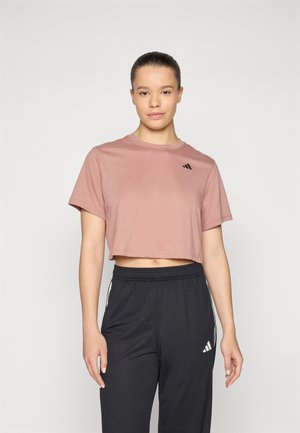 Camiseta corta rosa con mangas cortas y un logo negro en el pecho, combinada con pantalones de chándal negros que tienen rayas laterales blancas.