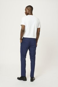 Camiseta blanca de manga corta, pantalones navy, zapatos negros. Los pantalones tienen un corte recto con bolsillos, tejido suave y costuras limpias.