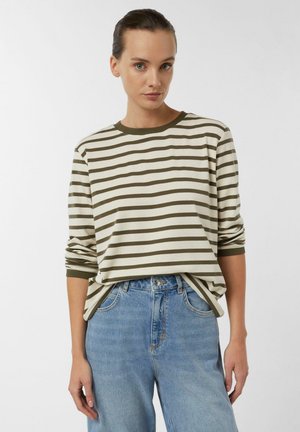 Gestreiftes Langarmshirt in Creme und Olivgrün mit rundem Ausschnitt und weichem Stoff. Kombiniert mit hellblauen Jeans.