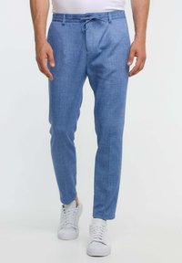 Pantalones ajustados de color azul claro, confeccionados con tela suave. Cuentan con cintura con cordón, bolsillos laterales y se combinan con zapatillas blancas.