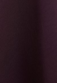 Tissu lisse d’une couleur violet profond uniforme avec une texture subtile, légèrement ombré du côté droit.