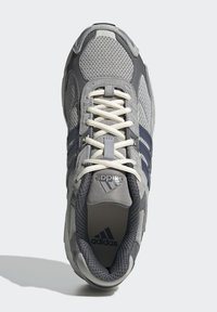 Sive mrežaste atletske tenisice s mornarsko plavim detaljima, imaju vezice, podstavljen jezik i Adidasov logo na jeziku i sa strane.