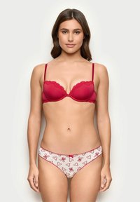 Roter gepolsterter BH mit Spitzenbesatz und verstellbaren Trägern, kombiniert mit weißen Slips mit roten Herzmustern und zarten Akzenten.