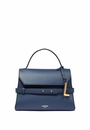 Sac à main en cuir bleu marine avec poignée supérieure, rabat avant, détail de ceinture mince et charme en forme de L doré sur fond blanc.