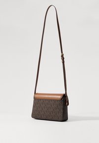 Hnědá kožená a vzorovaná plátěná crossbody taška s nastavitelným popruhem, vybavená klopovým zavíráním a logo akcenty. Kompaktní obdélníkový tvar.