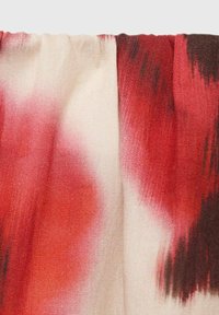 Textile with a soft, lightweight weave featuring a blend of red, orange, and cream colors, showcasing abstract patterns and a slightly textured surface.
