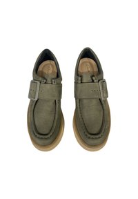 Chaussures en cuir vert avec un bout arrondi, une sangle et un détail de boucle, et une semelle en caoutchouc brun clair. Tige texturée et doublure intérieure lisse.