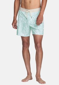 Muntgroene zwemshorts met een wit geometrisch patroon, elastische tailleband en koordsluiting. Lichtgewicht stof en lengte boven de knie.