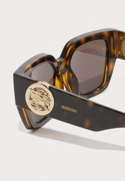 Occhiali da sole tartarugati con montatura quadrata, lenti scure, dettaglio in oro sul braccio e marchio "BURBERRY" in lettere dorate.