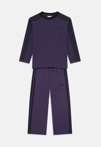 Chándal de algodón morado con mangas largas, acentos de rayas negras y un pequeño logo negro en el pecho y en la pierna izquierda del pantalón.