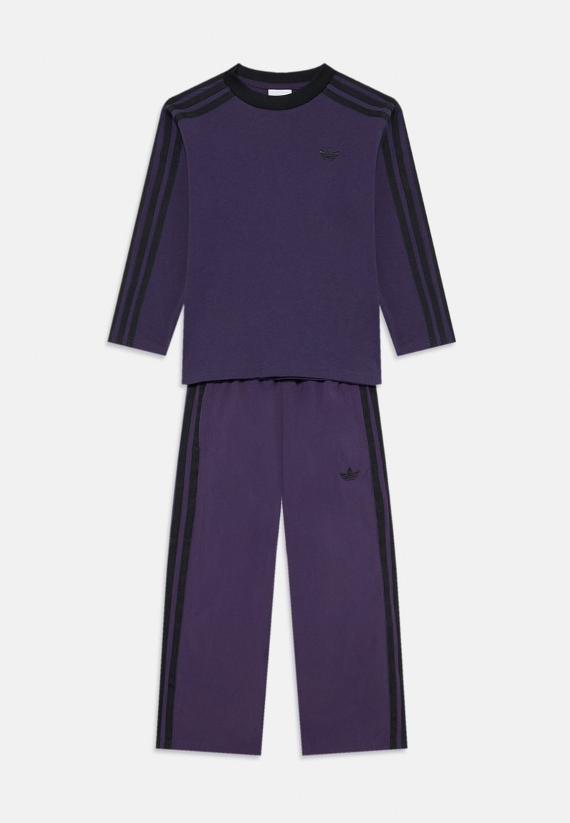 Chándal de algodón morado con mangas largas, acentos de rayas negras y un pequeño logo negro en el pecho y en la pierna izquierda del pantalón.