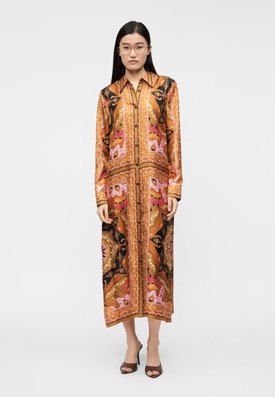 Ilga raštuota marškinių suknelė rudos, koralinės ir rožinės spalvų, su gėlių raštais, sagų užsegimu, apykakle ir ilgomis rankovėmis. Dėvima su aukštakulniais batais.