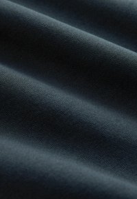 Mörkblå texturerad tyg med ribbad yta, som visar mjuka veck och en slät utseende, lämplig för olika textiltillämpningar.
