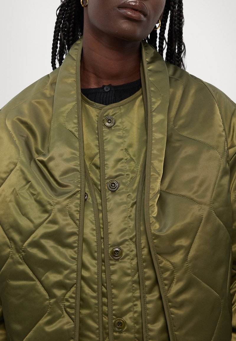 Olivgrüne gesteppte Jacke mit satinierter Oberfläche, featuring eine Knopf-Schließe, gerippten Kragen und einer entspannten Passform mit sichtbaren Nähten.